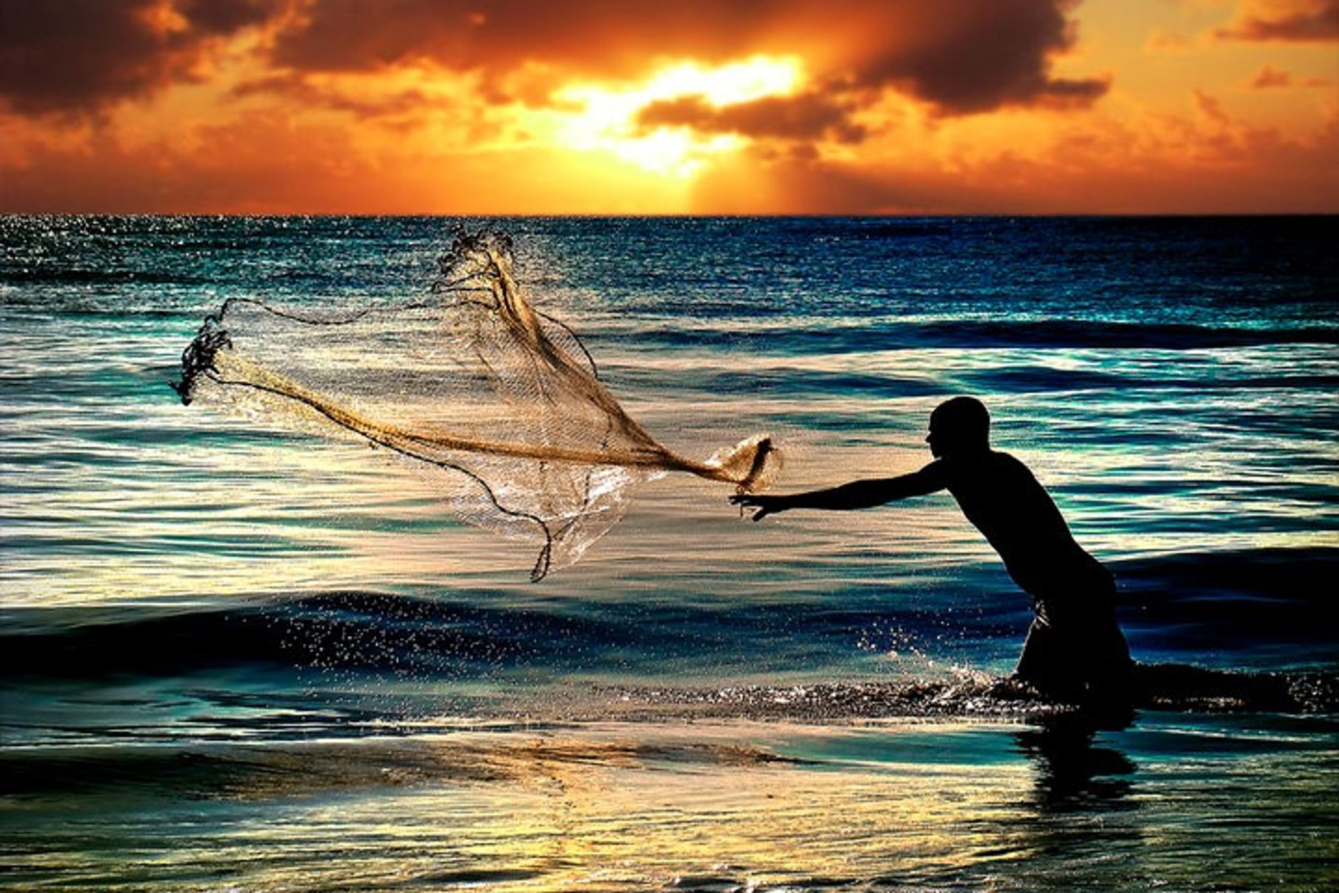 Pescador lançando a rede ao pôr do sol no mar da Península de Maraú