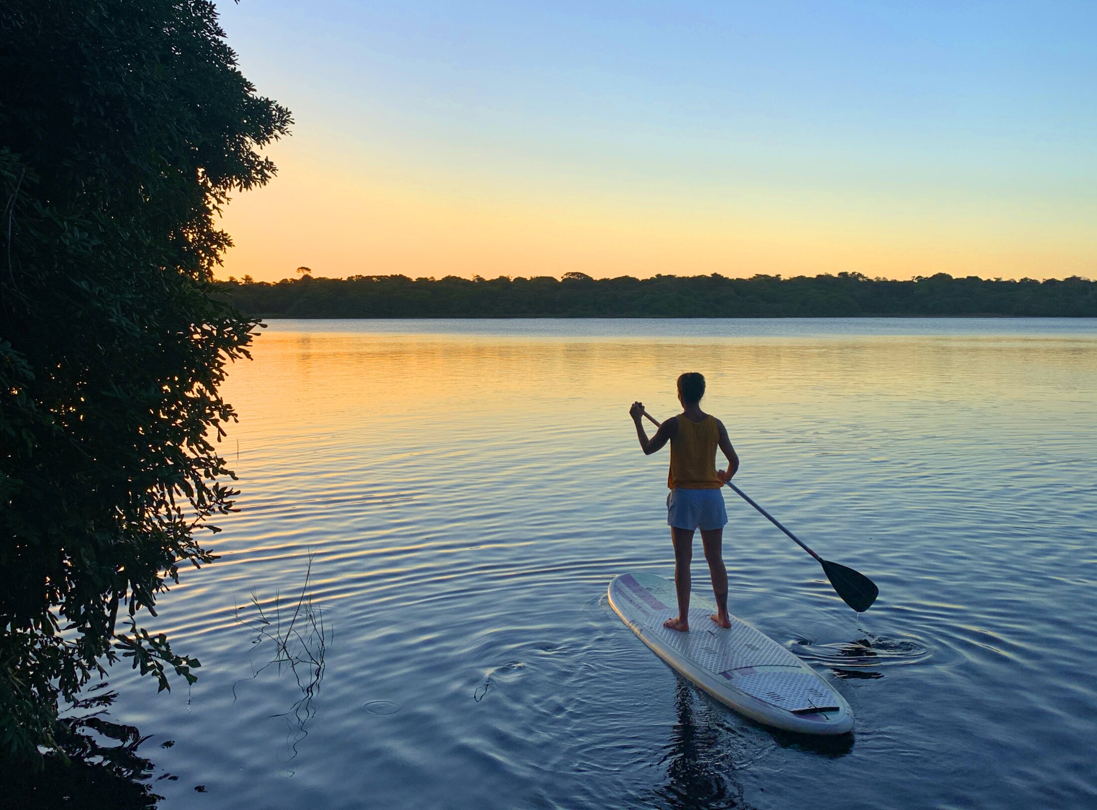 Stand up paddle ao pôr do sol nas águas calmas da Lagoa do Cassange