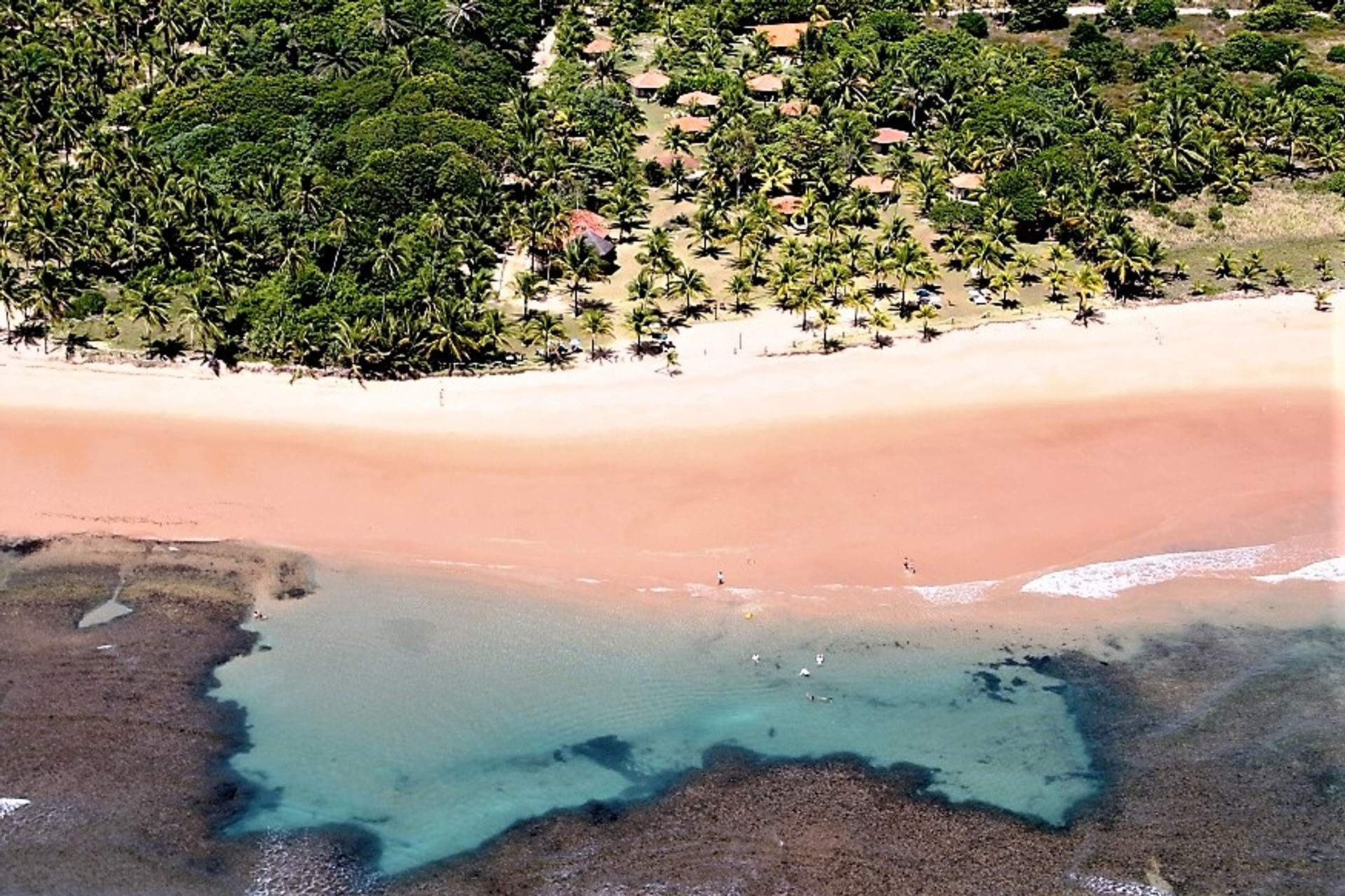 Piscina natural de águas turquesa em frente à pousada, vista aérea